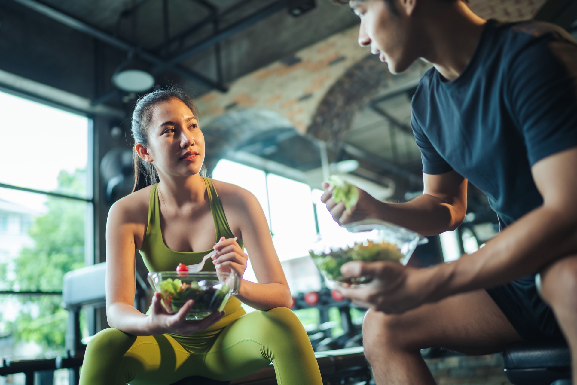 wo Asian people healthy eating salad after exercise at fitness gym.